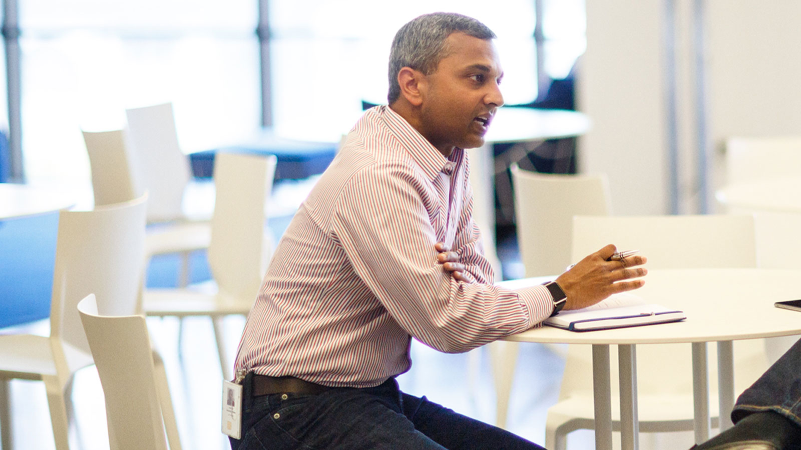 A man sitting at a desk who is having conversation with others.