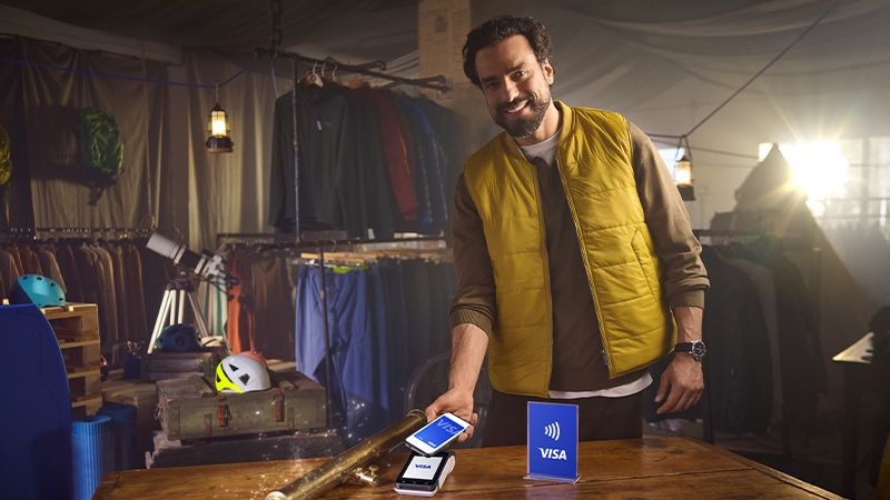 man paying with Visa on mobile in store